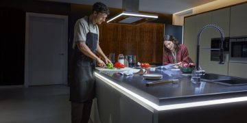 Luminárias e tiras de luz Philips Hue iluminam uma sala moderna com tons quentes e acolhedores.