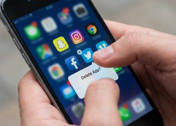 Pessoa a apagar aplicações de redes sociais do telemóvel ilustrando abandono progressivo de plataformas digitais
