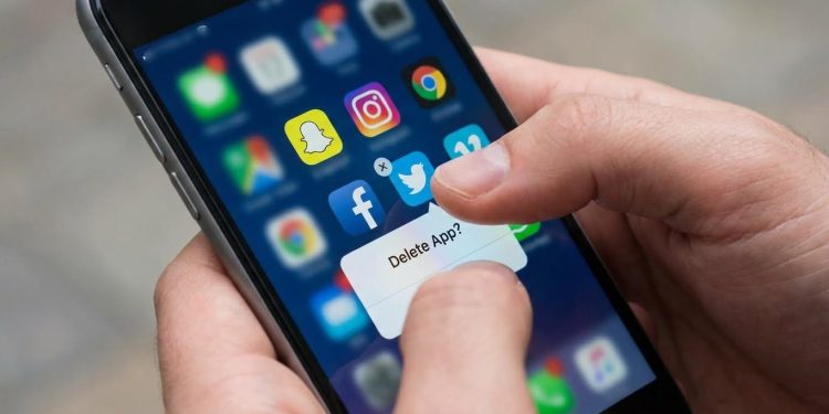 Pessoa a apagar aplicações de redes sociais do telemóvel ilustrando abandono progressivo de plataformas digitais