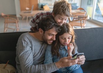 criança a usar tablet educativo com acompanhamento de um adulto num ambiente familiar