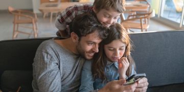 criança a usar tablet educativo com acompanhamento de um adulto num ambiente familiar