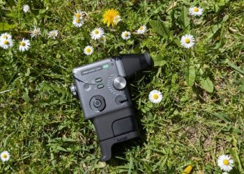 Fujifilm Instax Mini Evo Cinema em estilo de câmara cine vintage Super-8 com acessório de visor e punho acoplados, sobre fundo claro neutro