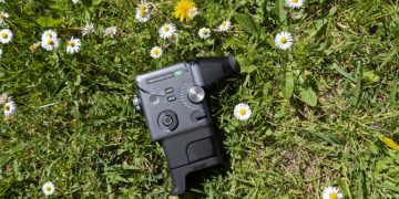 Fujifilm Instax Mini Evo Cinema em estilo de câmara cine vintage Super-8 com acessório de visor e punho acoplados, sobre fundo claro neutro