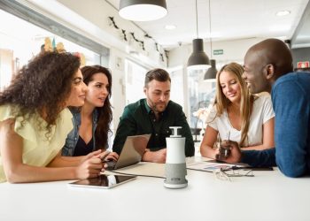 Dispositivo RICOH Meeting Hub 360 numa sala de reuniões híbrida com participantes presenciais e remotos