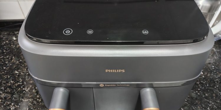 Análise Philips Air Fryer 3000: duas gavetas, nove litros 1 Philips Air Fryer Série 3000 Cesta Dupla NA352/00 em cinzento mate com detalhes metálicos dourados sobre bancada de cozinha moderna, com as duas gavetas abertas e o ecrã táctil iluminado
