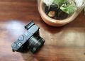 Sony RX1R III em magnesio preto mate sobre mesa de madeira, com a lente Zeiss Sonnar 35mm f/2 em destaque e o visor EVF fixo