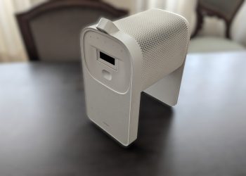 Samsung The Premiere 5 em modo interactivo sobre mesa, com a base Touch Stand encaixada e a projecção táctil activa numa superfície de trabalho, em ambiente de sala com luz controlada