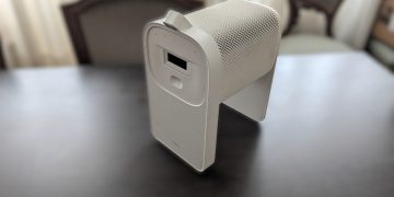 Samsung The Premiere 5 em modo interactivo sobre mesa, com a base Touch Stand encaixada e a projecção táctil activa numa superfície de trabalho, em ambiente de sala com luz controlada