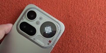 Nothing Phone 4a Pro em prata polido sobre superfície escura, com o módulo de câmara transparente e o Glyph Matrix circular activo a mostrar o relógio