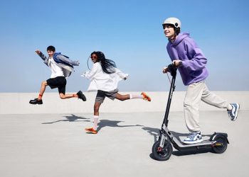Trotinete eléctrica Segway Ninebot E3 em circulação numa avenida urbana, destacando a mobilidade urbana e o design moderno.