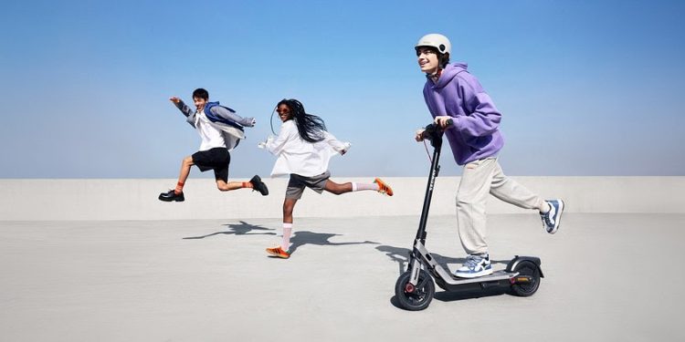 Trotinete eléctrica Segway Ninebot E3 em circulação numa avenida urbana, destacando a mobilidade urbana e o design moderno.